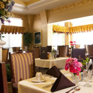 An elegant dining room with neatly set tables, adorned with vibrant floral arrangements.