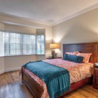 A cozy bedroom with a large bed, wooden furniture, and soft lighting.