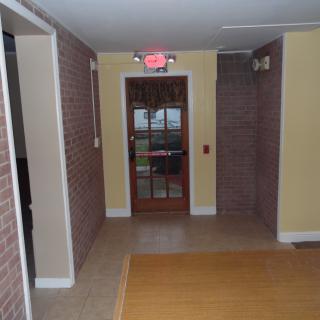 A hallway featuring brick walls and a door with an exit sign above.