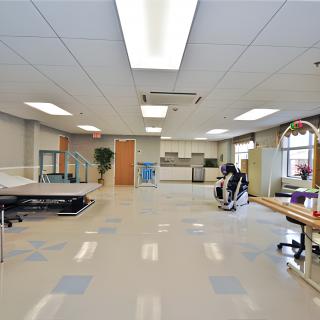 A spacious rehabilitation center equipped with various exercise machines and therapy tools.