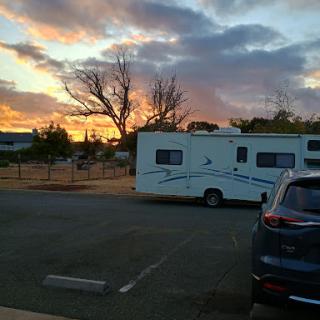 A serene sunset view featuring an RV parked in a campground.