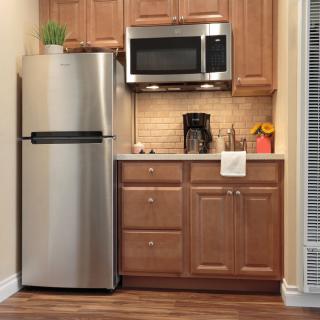 A compact kitchen setup with a refrigerator, microwave, and wooden cabinets.