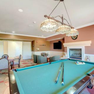 A cozy recreation room featuring a pool table, chandelier lighting, fireplace, and a seating area with a television.