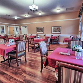 A cozy dining room with neatly arranged tables covered in red tablecloths.