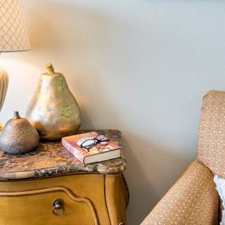 A cozy living room setup featuring a lamp and decorative pear ornaments on a side table.