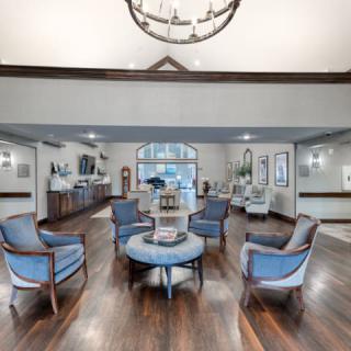 A spacious and elegantly designed lobby with a circular seating arrangement and hardwood flooring.