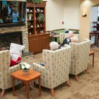 Elderly individuals seated in a cozy living room, watching TV together.