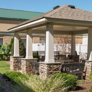 A beautifully designed gazebo with stone pillars, offering a shaded area for outdoor relaxation.