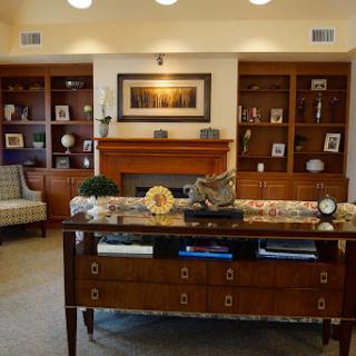 A cozy living room setup featuring elegant furniture, a warm fireplace, and decorative shelves.