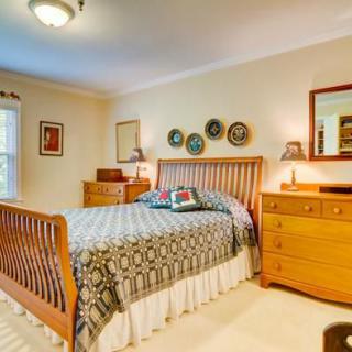A cozy bedroom with a wooden bed, matching dresser and mirror, featuring decorative wall plates and warm lighting.