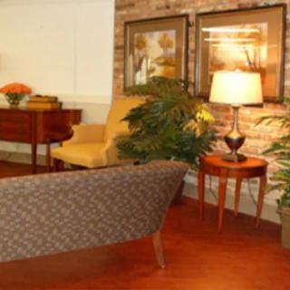 A cozy living room featuring a patterned sofa, side table with a lamp, and framed artwork on the wall.