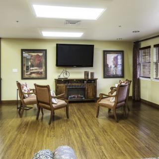 A cozy living room with wooden chairs arranged around a TV and fireplace.