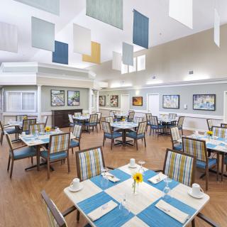 A modern and spacious dining room with neatly arranged tables and colorful ceiling panels.