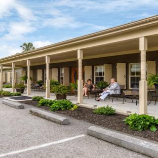 A view of a motel with a covered porch and outdoor seating area.