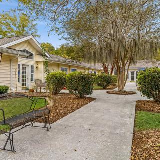 A serene outdoor pathway surrounded by trees and buildings, featuring a bench for relaxation.