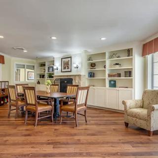 A cozy living and dining area with wood flooring, built-in bookshelves, and classic furniture.