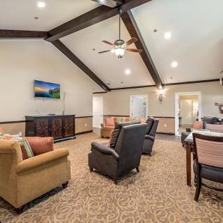A spacious living room with comfortable seating, a ceiling fan, and a television.