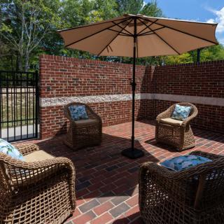 A peaceful outdoor patio setup featuring wicker chairs and a large umbrella, perfect for relaxation on a sunny day.