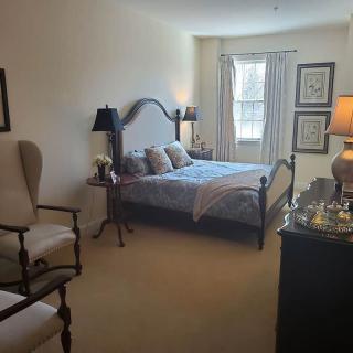 A cozy bedroom with a large window, elegant furniture, and soft lighting.