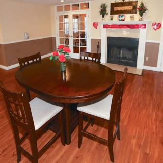 A cozy dining area with a round wooden table and chairs, adorned with Valentine's Day decorations, featuring a fireplace in the background.