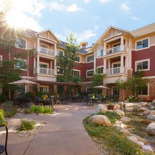 A scenic view of a residential building with a well-maintained courtyard, bathed in sunlight.