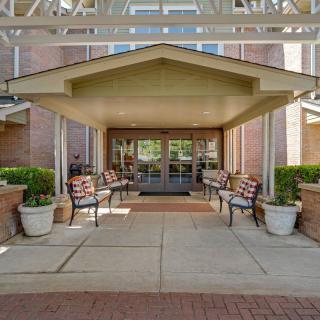 Entrance to a building with benches and planters under a canopy.