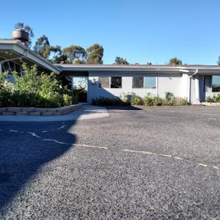 A bright day showcasing a modern building with a landscaped parking lot.
