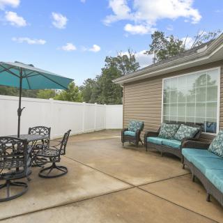 A spacious patio with outdoor furniture and an umbrella, set against a sunny backyard.