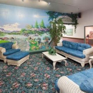 A cozy living room with blue upholstered furniture and a vibrant mural on the wall.