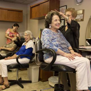 A group of senior women enjoying a day at the hair salon as stylists work on their hair.