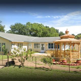 A house with a charming gazebo and garden in the front yard under a clear blue sky.