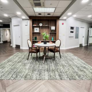 A cozy modern living area featuring a stylish table and chairs, complemented by a decorative plant and elegant shelving.