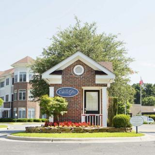 A small brick entrance building surrounded by landscaping, leading to a residential complex.