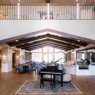 A spacious lobby area featuring a grand piano, with elegant furniture and exposed ceiling beams.