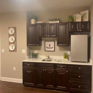 A cozy kitchen area with dark cabinets, a small refrigerator, and decorative wall art.