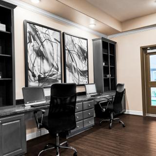 A modern home office setup with dual workstations and abstract artwork.