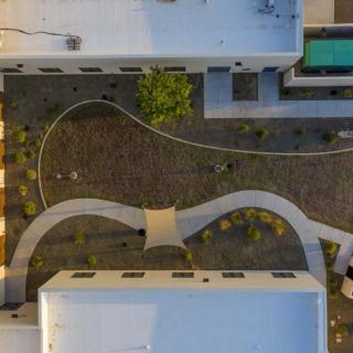 Aerial view of a modern architectural complex featuring a landscaped courtyard and winding pathways.