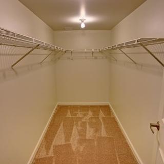An empty walk-in closet with wire shelving and simple lighting.