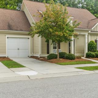 A suburban house with an attached garage and a tree in the front yard.