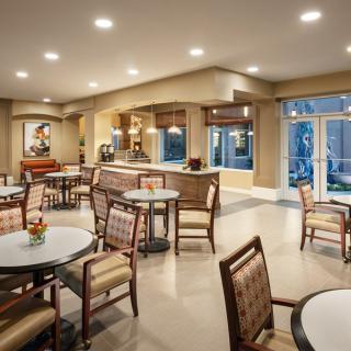 A cozy dining area with neatly arranged tables and chairs, illuminated by warm indoor lighting.