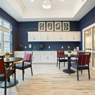 A modern kitchen and dining area with sleek furniture, wood flooring, and elegant light fixtures.