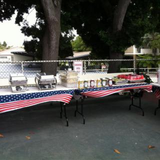 Outdoor buffet table setup with American flag tablecloths.