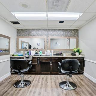 A modern barbershop interior with two chairs facing large mirrors.
