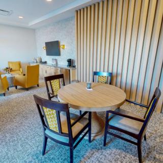 A modern living room with a round table and chairs, featuring a seating area with a television.
