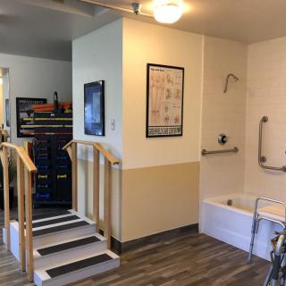 An accessible bathroom setup with safety rails and a step ramp for easy access.