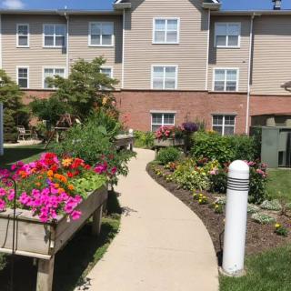 A vibrant garden with a variety of flowers along a winding pathway beside a residential building.