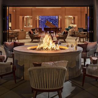 A stylish outdoor lounge area featuring a central fire pit surrounded by comfortable seating, perfect for a cozy evening gathering.