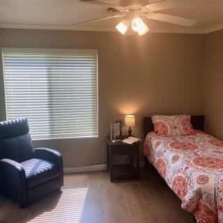 A cozy bedroom with a single bed and recliner chair under soft lighting.