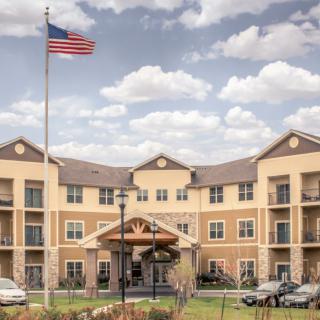 A large hotel building with an American flag flying in front, set against a partly cloudy sky.