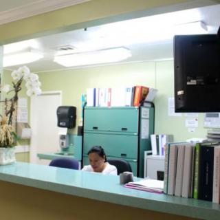 A reception area with a person working at a desk, surrounded by books and office supplies.